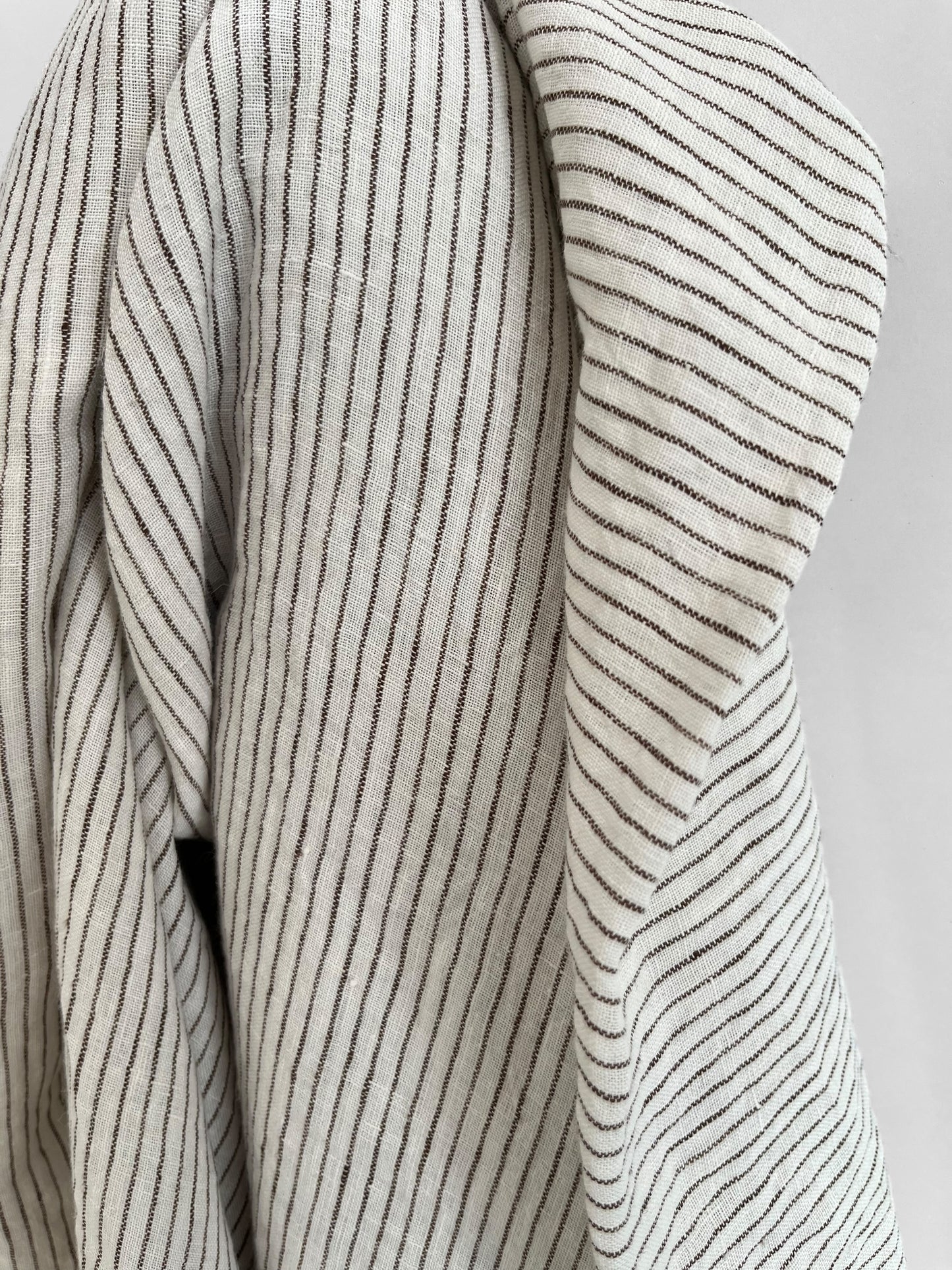 Close-up of a striped fabric with brown and white lines on a neutral background