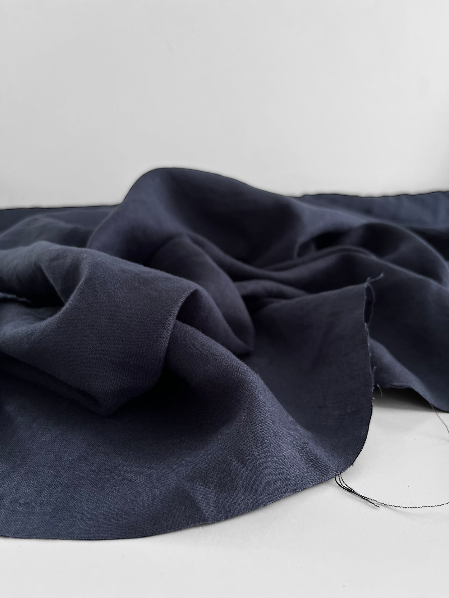 Navy blue fabric draped over a white surface with a neutral background