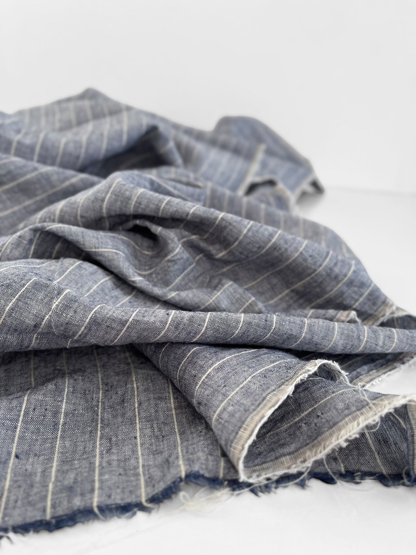Folded blue fabric with white stripes on a light gray background