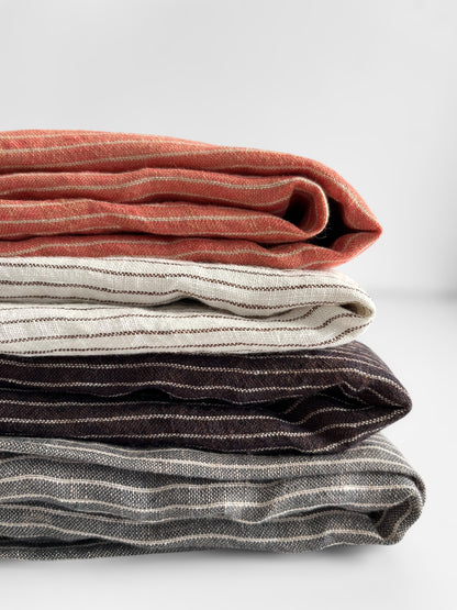 Stack of folded striped fabric  in various colors on a light background