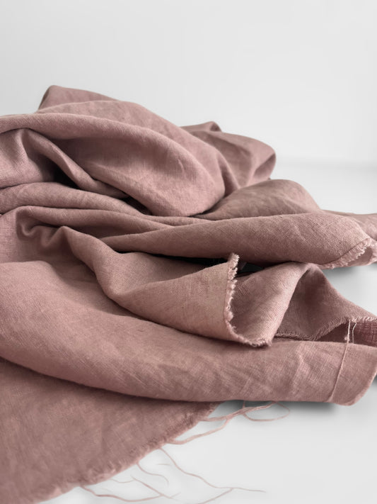 Folded mauve pink linen fabric on a light gray background