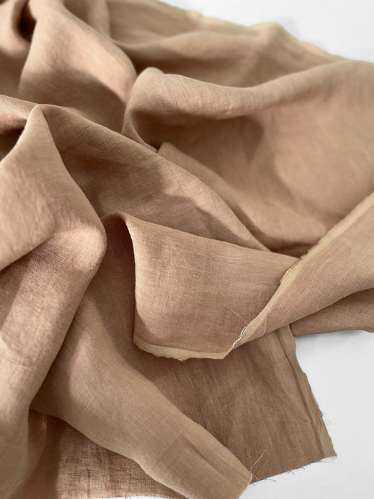 Beige linen fabric with a soft texture on a white background