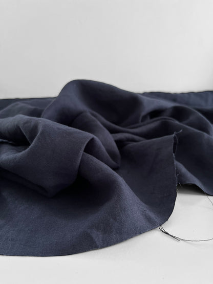 Navy blue fabric draped over a white surface with a neutral background