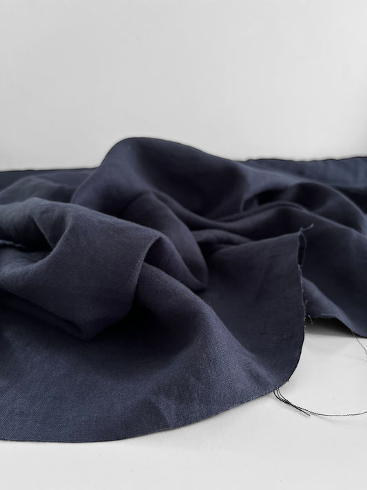 Navy blue fabric draped over a white surface with a neutral background