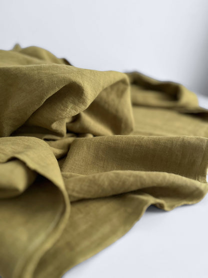 Folded green linen fabric on a white background