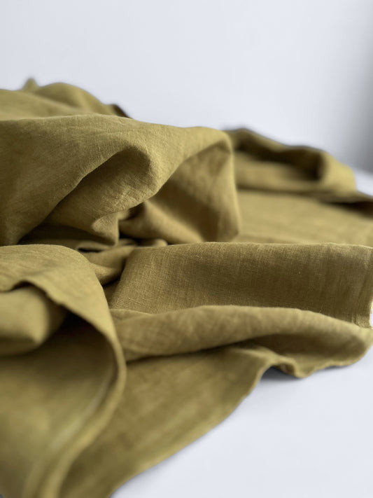 Folded green linen fabric on a white background