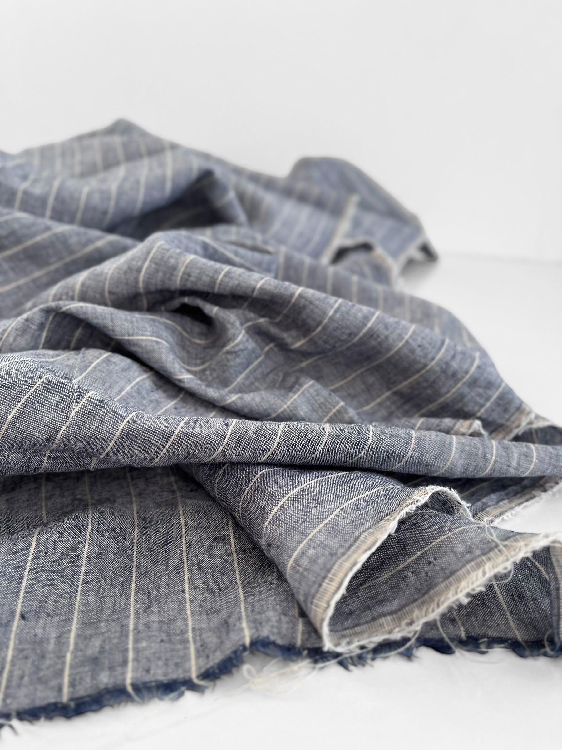 Folded blue fabric with white stripes on a light gray background