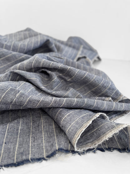 Folded blue fabric with white stripes on a light gray background
